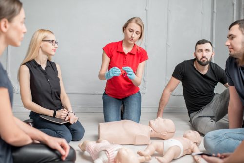 Young woman instructor showing valve for artificial respiration during the first aid group training indoors